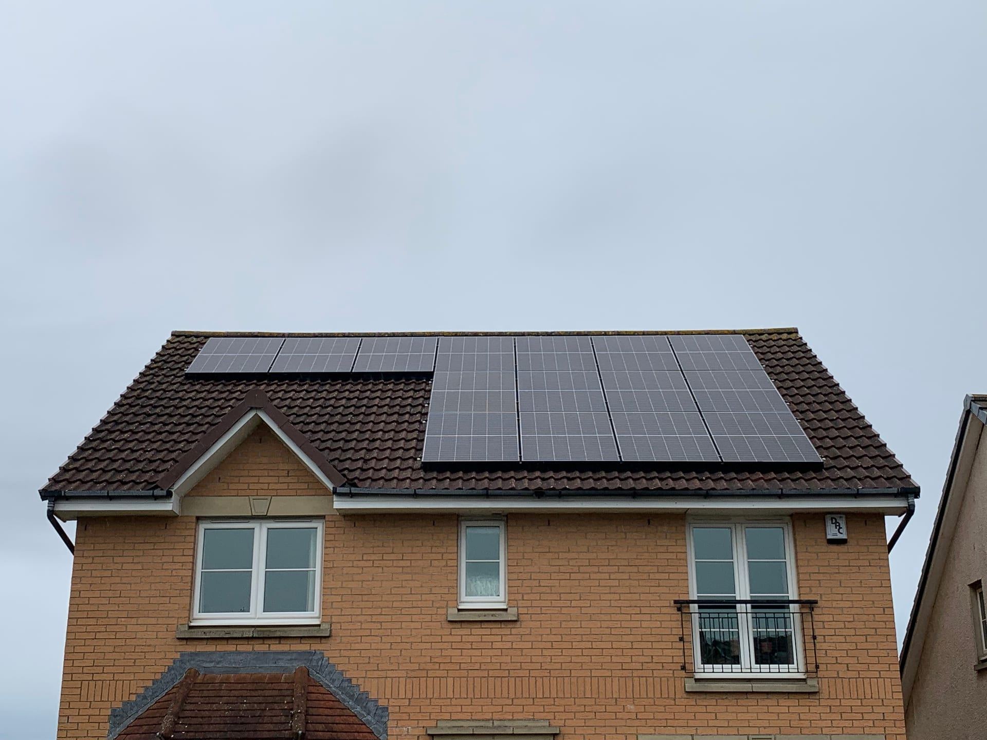 All-black solar panels fitted across the roof of a detached brick house